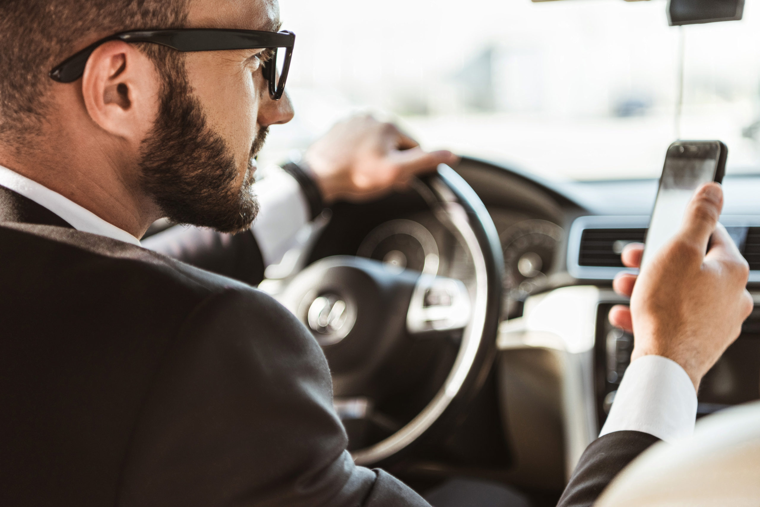 handsome driver in suit driving car and holding sm DMKMH8F scaled 1