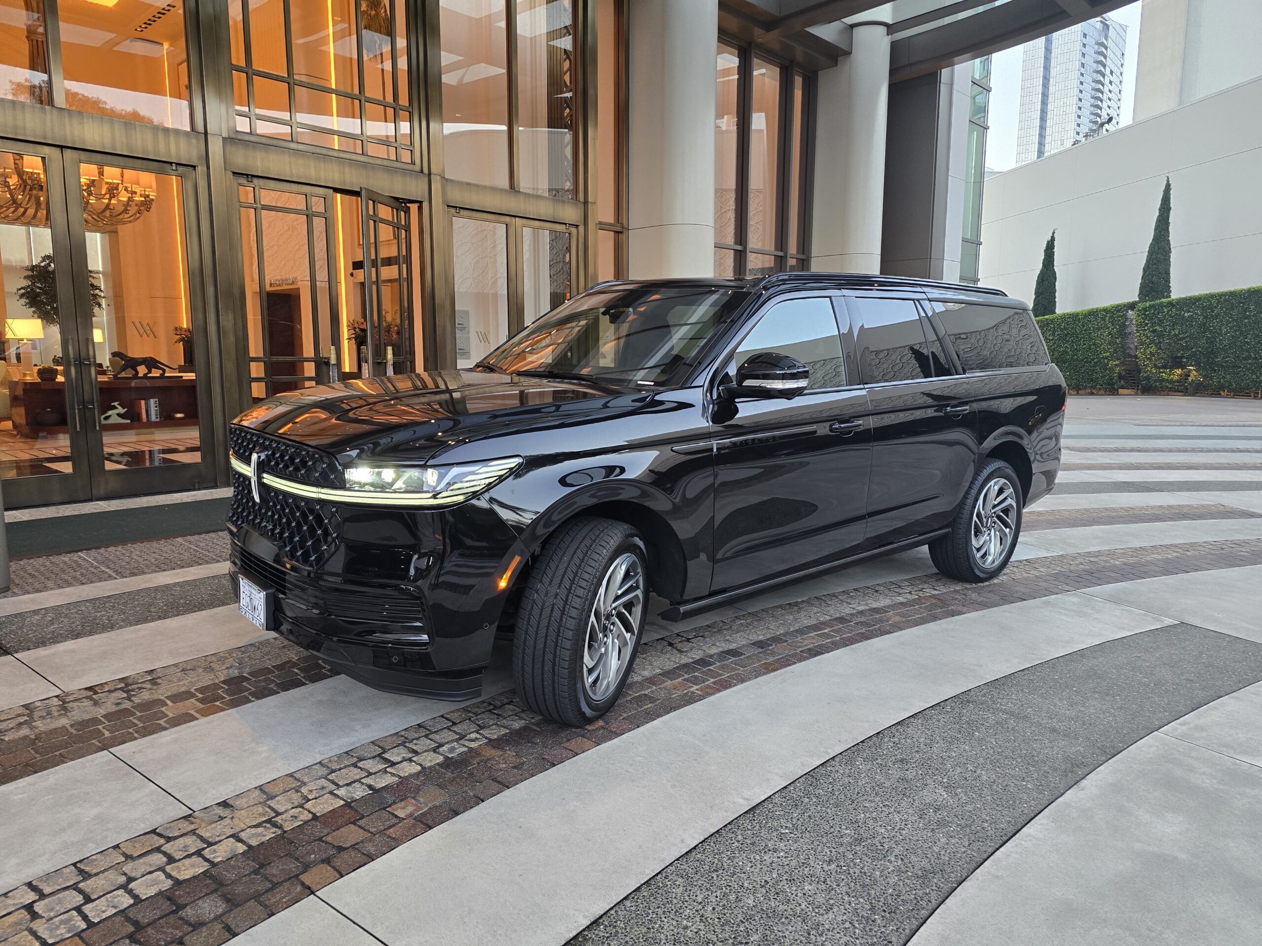 A sleek black SUV parked at the entrance of a luxury hotel, showcasing modern design elements and elegant surroundings.