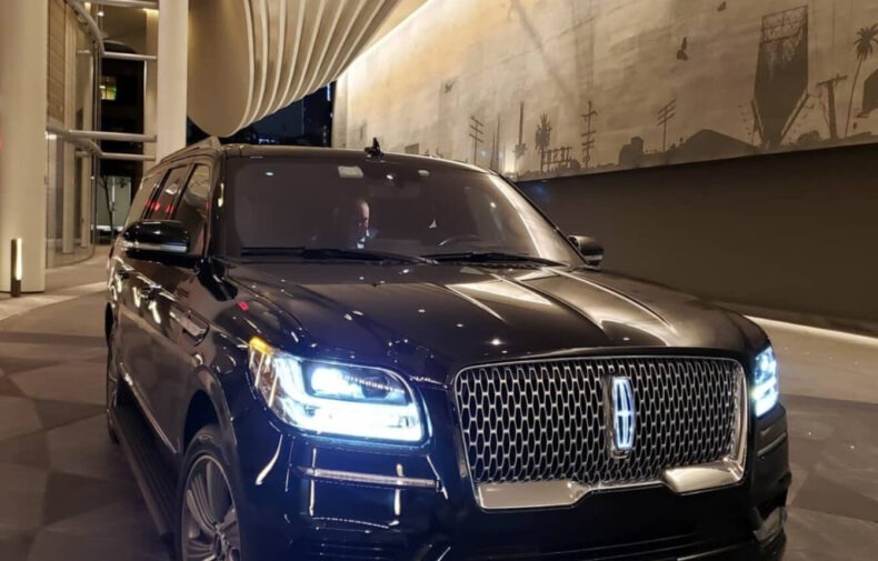 A sleek black Lincoln Navigator parked under dramatic architectural lighting, showcasing its luxury features against an urban backdrop.
